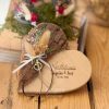 Personalisiertes Ringkissen aus Holz in Herzform mit zwei verschiedenfarbigen Bändern zum Befestigen der Eheringe für Braut und Bräutigam.