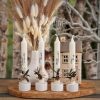 Vier dekorierte weiße Weihnachtskerzen mit festlichen Schriftzügen, Blumen und Holzmotiven als kleines Weihnachtsgeschenk.
